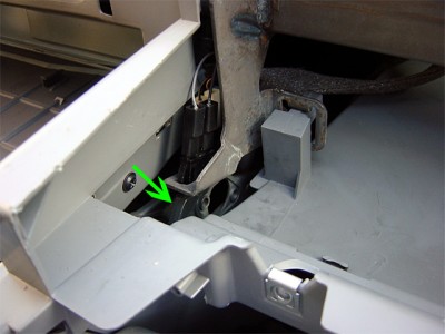 Le contacteur montré par la flèche verte ainsi que ses deux connecteurs. Les deux connecteurs blancs visibles derrière sont ceux du rangement central inférieur.